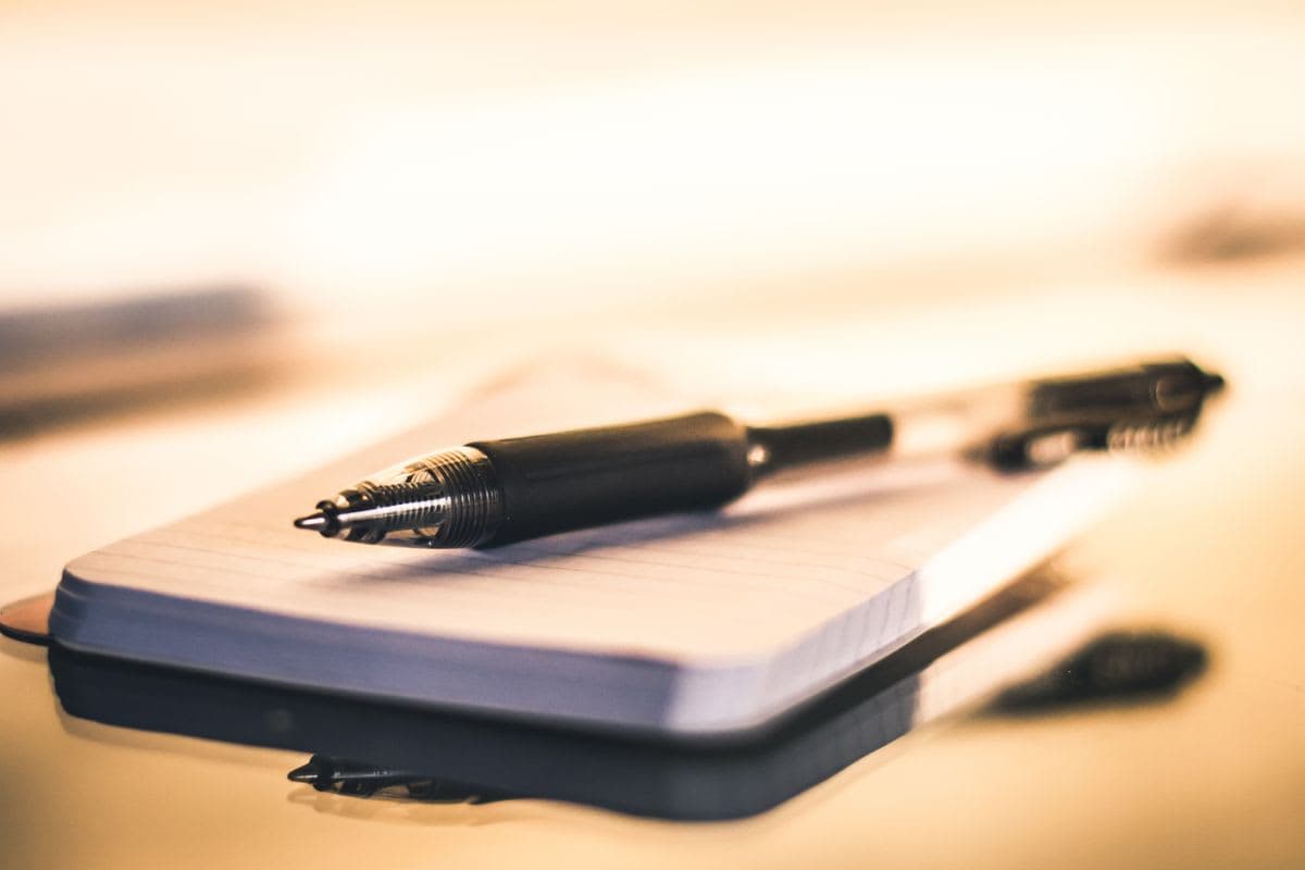 Notizblock und Stift auf einem Tisch: Kriterien für die Auswahl eines Kassensystems notieren