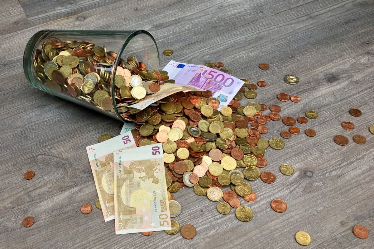 Umgekipptes Glas mit Euro-Münzen und Scheinen: Kassendifferenz beim Zählen