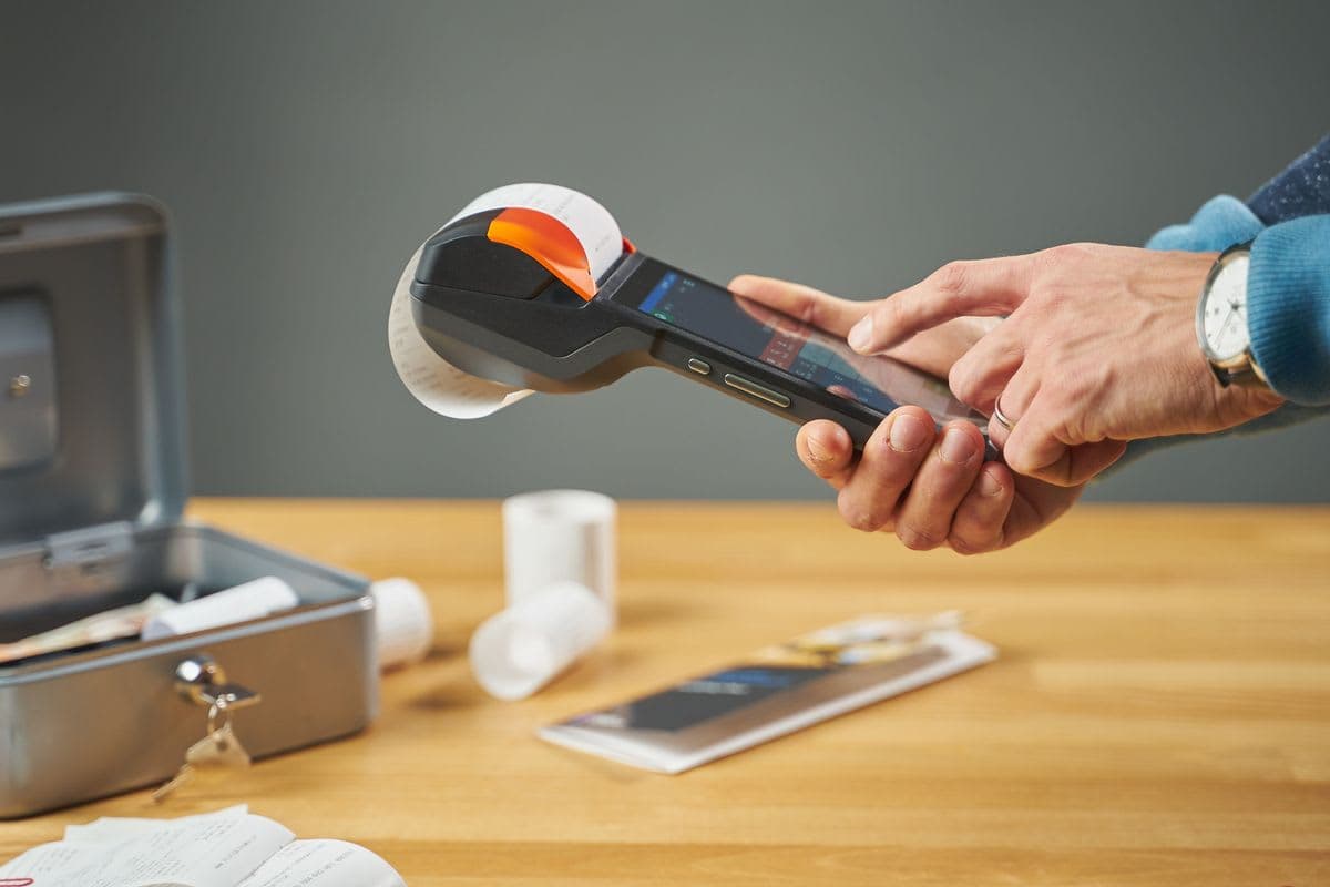 Mobiles Kassenterminal druckt einen Beleg, daneben eine geöffnete Geldkassette